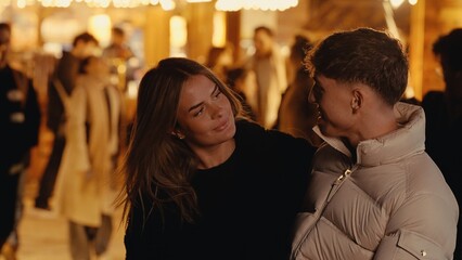 A young couple in Paris France share a romantic moment at night The urban scene is illuminated by...