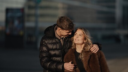 A young couple embraces in Paris France enjoying a romantic moment together outdoors in an urban setting The man and woman are dressed in stylish jackets and coats showcasing affection and love in thi