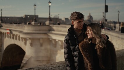 A young couple embraces on a bridge in Paris France with the cityscape in the background The image conveys love travel and relationships in a European urban setting.