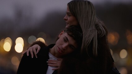 A romantic couple embraces in Paris France at night with city lights creating a bokeh effect in the background The young lovers share a moment of affection in this urban setting perfect for travel and