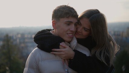 A romantic couple embraces in Paris France with a cityscape view in the background The young woman is hugging the man showcasing love and affection in an urban setting perfect for travel and relations