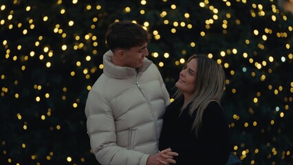 A romantic couple embraces in Paris France with a beautiful bokeh background of Christmas lights The young man and woman are in love enjoying the winter holiday season in the city.