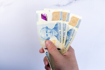 Hand holding 20,000-peso bills of the Argentine currency.