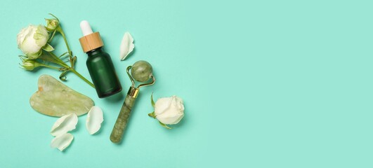 Beautiful white roses, bottle of cosmetic product, massage roller and guasha on turquoise...