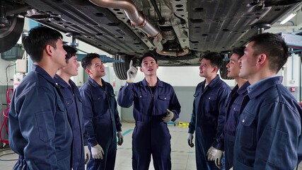 mechanics explaining vehicle undercarriage inspection procedure in garage | automotive, training, education, repair, industry theme
