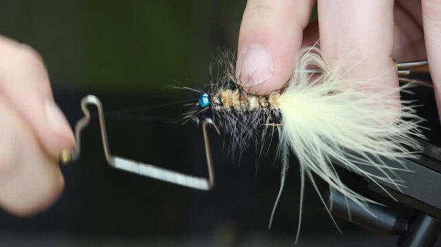close up of tying a wooly bug for fly fishing, whip finishing knot of a lifelike fly fishing lure