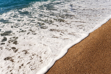Wide foamy wave spreading over the beach sand in a diagonal pattern showing the dynamic movement of the ocean tide