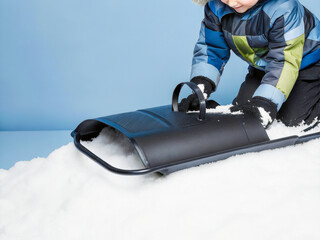 a young boy in a blue jacket and black pants is on a snowboard