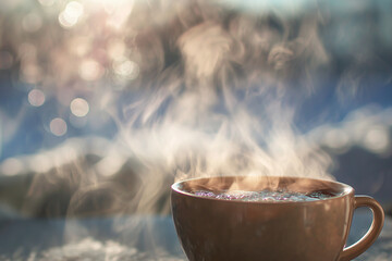 Hot water in a brown cup with steam rising against a blurred background
