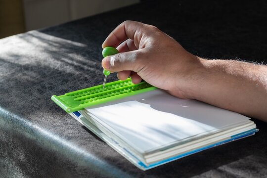 a hand writing on a Braille slate