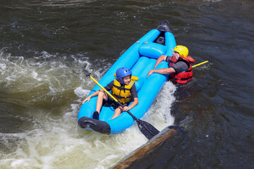 Father and son on a raft in whitewater rapids, father hanging on after falling in