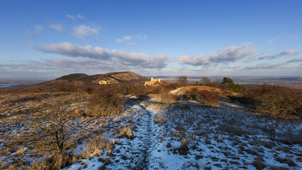 Winter panoramic view of Sirotci hradek and Palava ridge, snow-covered meadow under a blue sky, South Moravia, Czech Republic.