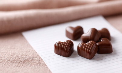 Heart Shaped Dark Chocolates Neatly Arranged on Beige Paper with Warm Sunlight. generative aI
