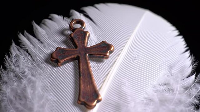A copper cross resting on a white feather against a black backdrop