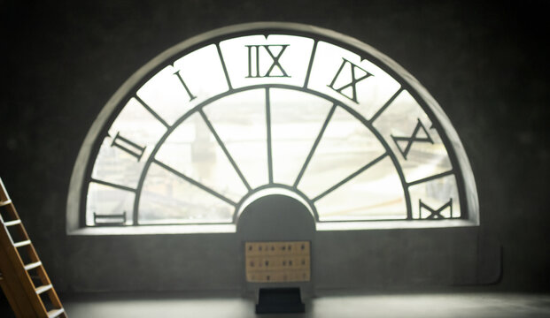 A blurry abstract background with an empty vintage room, a large semicircular window with a clock facing the city