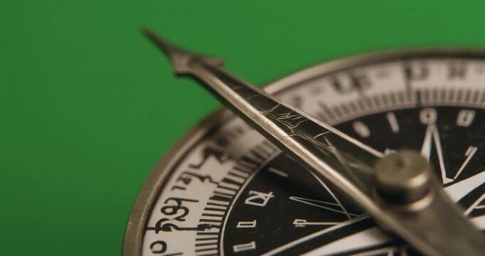 A close-up view of a compass on a green background with navigation details visible