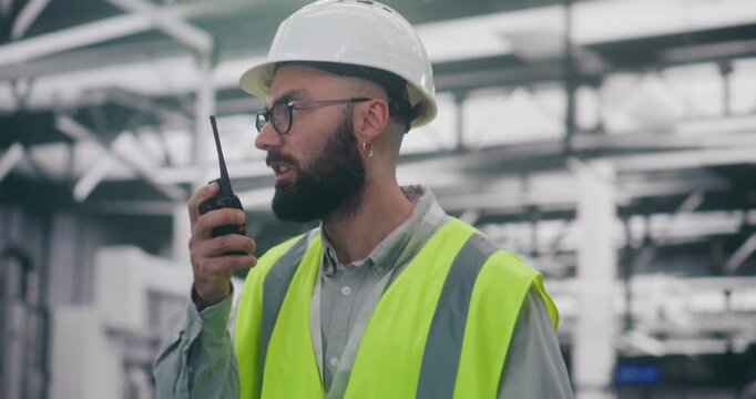 Industrial Management Engineer Directing Team With Radio. Specialist in Personal Protective Equipment Directs Personnel Using Radio in Large Industrial Setting. Management, Direction, Heavy Industry.