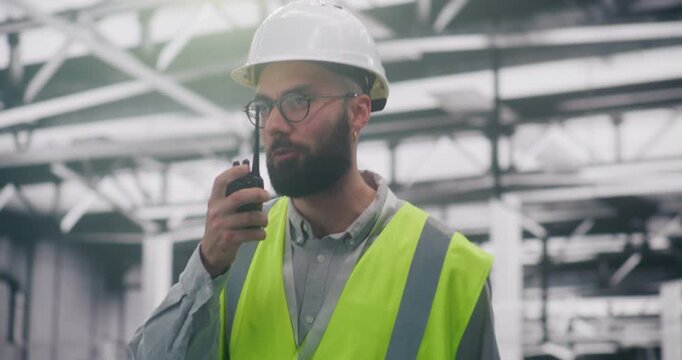 Safety Compliance Supervisor Reporting Conditions Via Two Way Radio. Focused Site Supervisor in Full Safety Gear Reports Work Conditions Using Two Way Radio In Facility. Concept Proactive Monitoring.