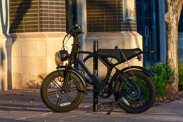An electric bicycle parked on a city sidewalk near a commercial building, illustrating urban micromobility, sustainable transportation options, and personal commuter mobility