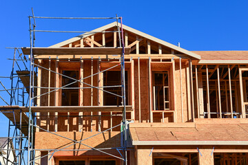 Residential building under construction with wooden framing and scaffolding, illustrating homebuilding progress, structural carpentry, and active housing development operations