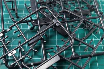 Abstract Backgrounds of Black Plastic Frame for Model Kit. Plastic model kit frame with green cutting mat background with striped pattern. Building Robot Model Kit