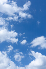 Obraz premium Fluffy white clouds, resembling cotton balls, float across a clear blue sky on a warm, sunny day. Background with ample copy space.