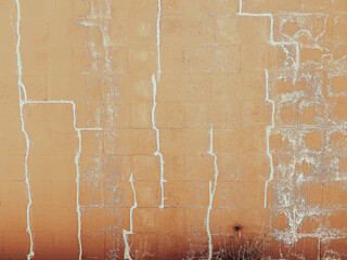 A weathered orange brick wall features white cracks and stains the rough surface and irregular lines give an aged and distressed appearance with hints of decay and texture