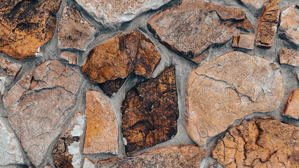 Several large rough stones fitted together form a solid wall their earthy brown and gray tones and irregular shapes create a rugged natural and textured appearance