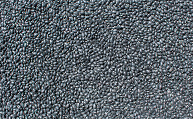 A large collection of shiny black beans fills the frame each bean smooth and oval creating a dense pattern that highlights their natural color texture and nutritious qualities
