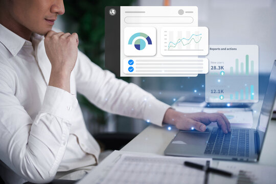 Adult Asian businessman analyzing digital data reports on laptop developing business strategy for growth success in modern corporate office