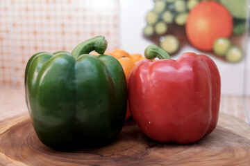 Fresh colorful bell peppers (red, green, yellow) on a wooden cutting board, healthy organic...