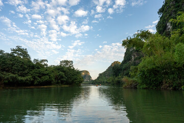 Obraz premium Peaceful River With Distant Rowing Boats and Karst Mountains in Trang An, Ninh Binh, Vietnam