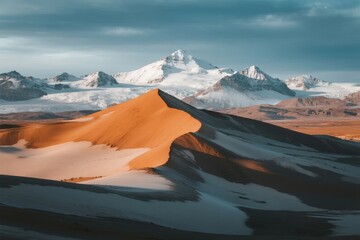 Sand dunes and snow-capped mountains under a dramatic sky
