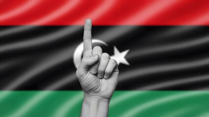 A hand with an index finger raised against the waving flag of Libya, symbolizing unity or victory.