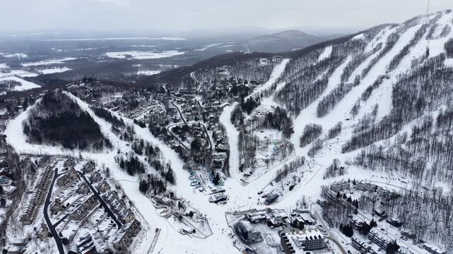 Aerial winter view of Bromont ski resort with snowy slopes, village and parking area in Quebec, Canada. g.