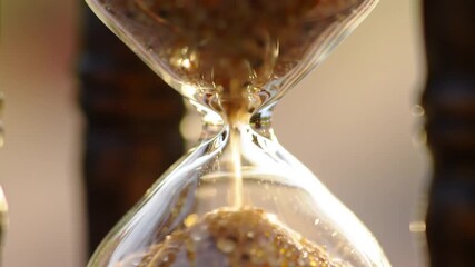 Hourglass with sand flowing from top to bottom, symbolizing the passage of time.
