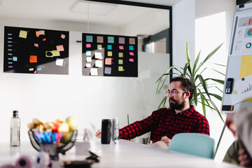 Business meeting with professionals collaborating in a modern office space, focusing on strategy and planning in a creative environment with colorful notes