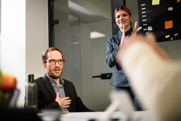 Business team members engage in a meeting with discussions and presentations in a modern office setting during the morning hours
