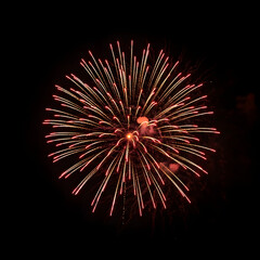 Obraz premium Vibrant red and orange fireworks exploding against a dark night sky with streaks of light radiating outward.