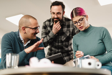 Business colleagues collaborating in a modern office setting while discussing plans and analyzing data on a tablet during a team meeting