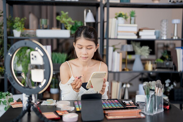 Asia woman beauty influencer makeup artist vlogger live streaming makeup tutorial on smartphone for social media