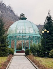 Glass pavilion housing Borjomi mineral water in Central Park, Georgia, featuring transparent walls, ornate details, and visitors enjoying the historic spa structure