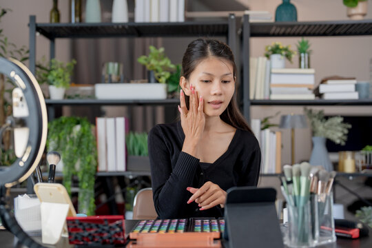 Asia woman beauty influencer makeup artist vlogger live streaming makeup tutorial on smartphone for social media