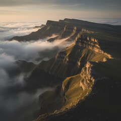 Majestic cliffs bathed in golden sunlight rise dramatically above a sea of white clouds.