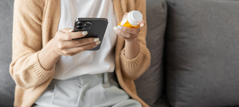 Young asian woman using smartphone Talk with doctor consulting online conference medical app on cellphone girl reading information online on mobile phonewith holding bottled drug