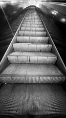 A close-up view of escalator steps in black and white, showcasing the texture and lines of the metal steps