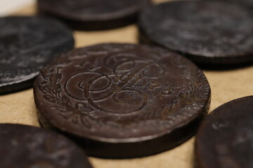 A close-up view of antique Russian Empire 5 kopecks of Catherine II coins with intricate designs, featuring ornate lettering and floral patterns, set against a neutral background