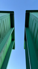 A low-angle view of two green containers against a clear blue sky