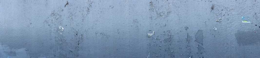 A close-up of a textured surface with peeling paint and a grayish hue, showcasing layers of color and wear