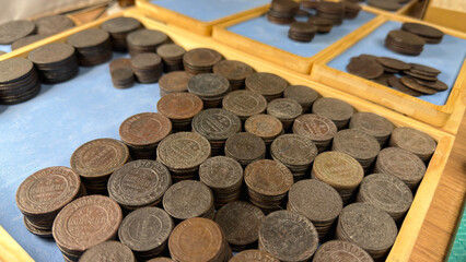 A collection of old Russian Empire coins arranged in wooden trays, showcasing various sizes and designs, with a focus on their aged, worn surfaces
